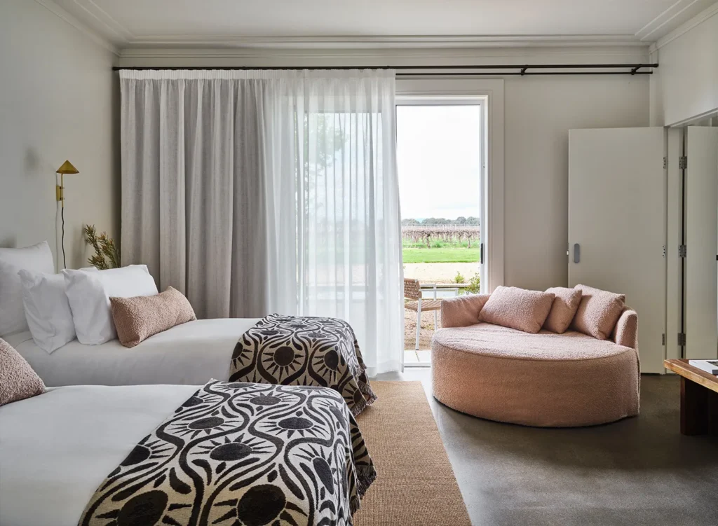 Comfortable luxury safari suite with soft bedding, stylish interiors, and large windows overlooking the Kenyan savannah.